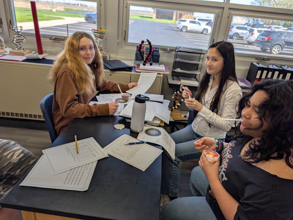three female students smiling with ice cream in their hands sitting at the science table