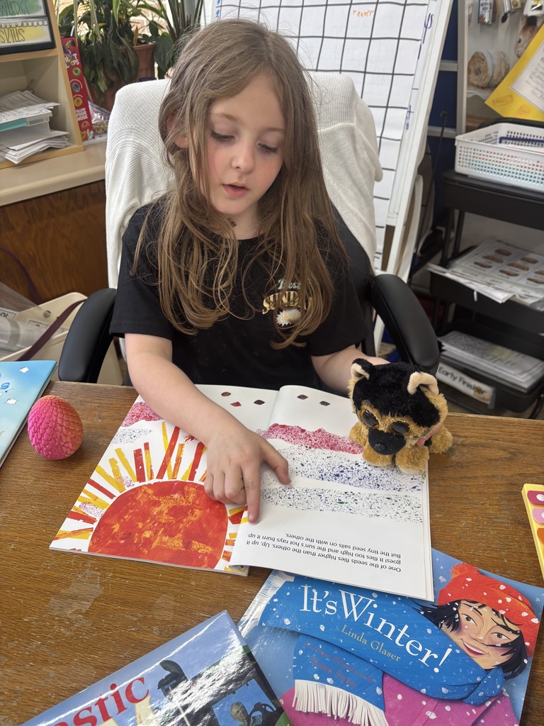 female student reading a book with her puppy stuffed animal