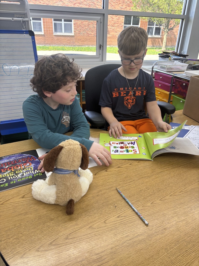 two male students reading a book together with a puppy stuffed animal