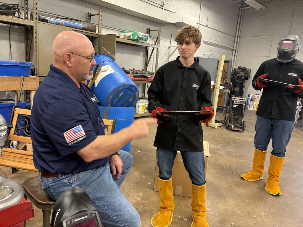 visitor working one on one with a student welding