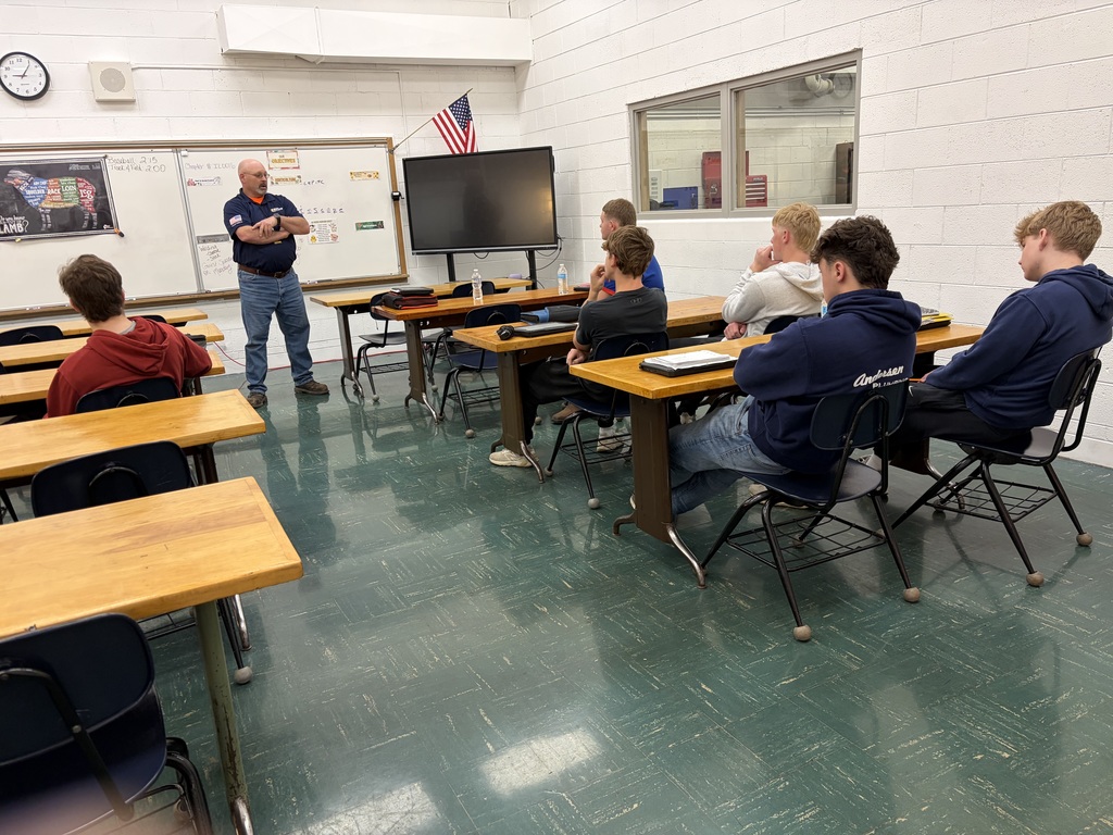 students sitting at desks with visitor speaking