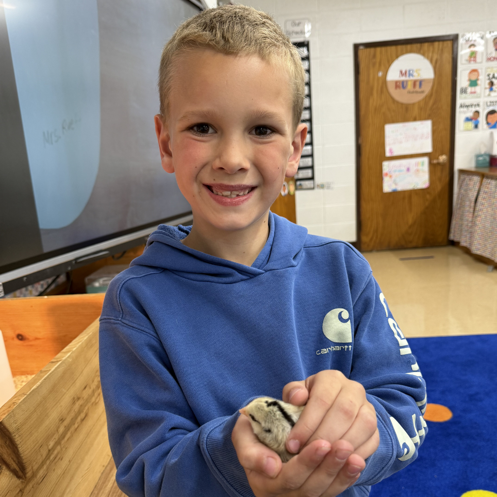 student holding chick smiling