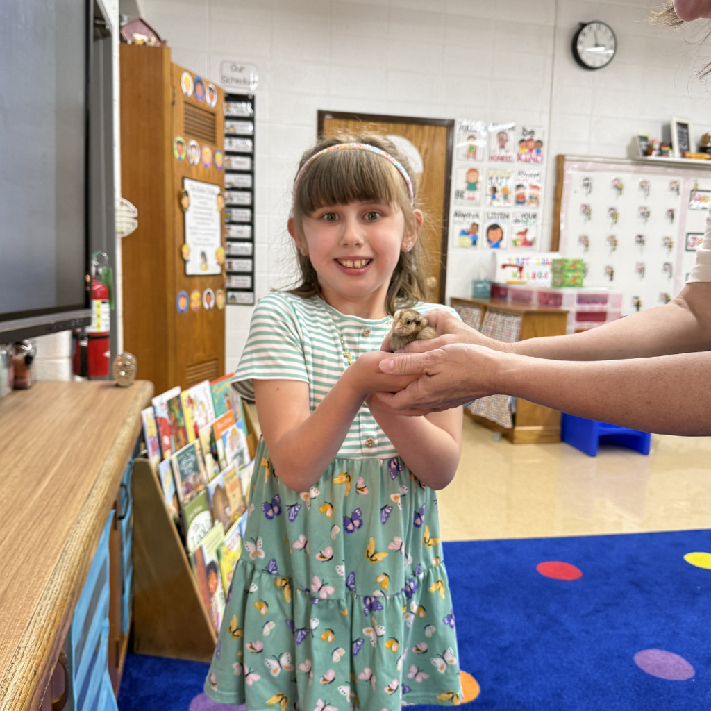 student holding chick smiling