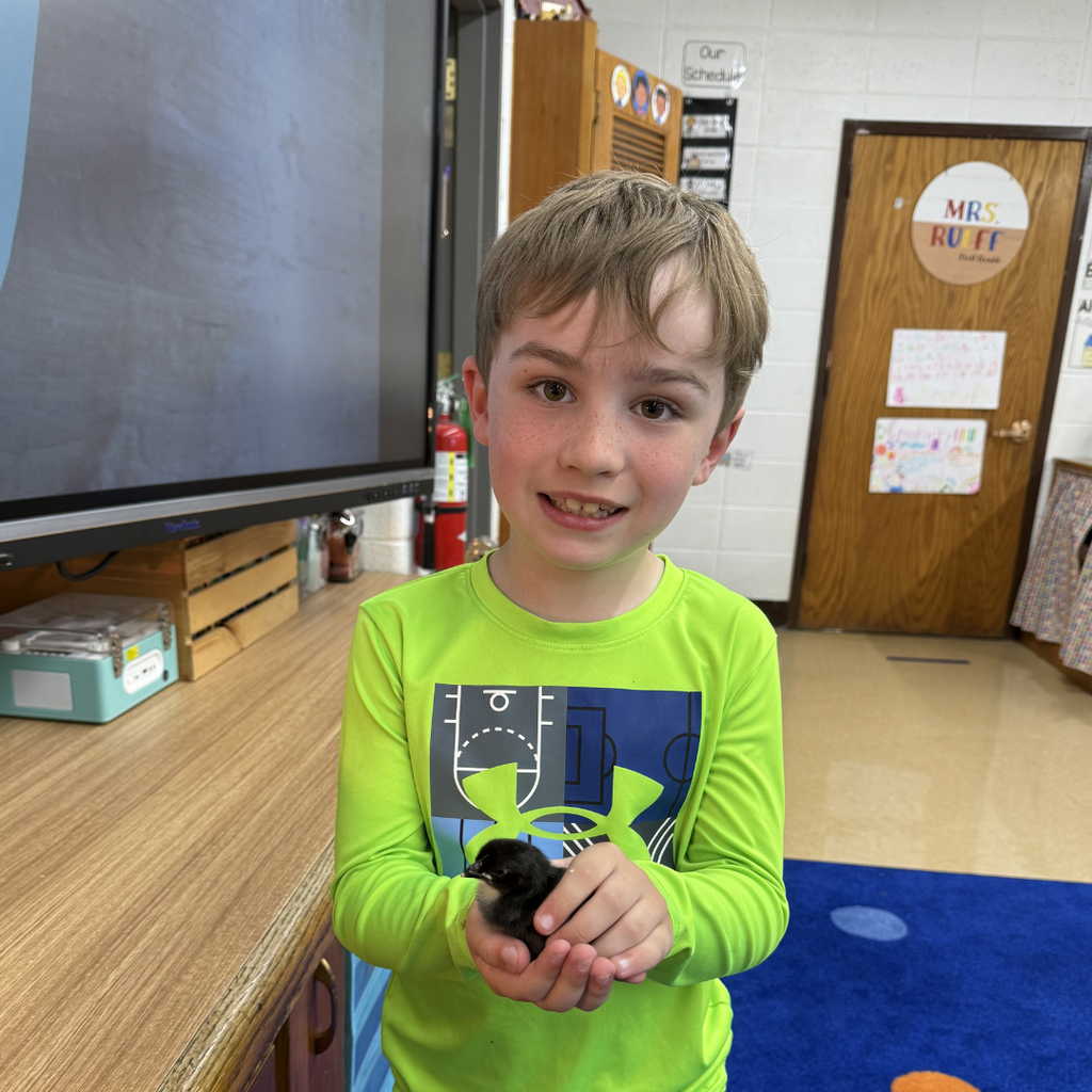student holding chick smiling