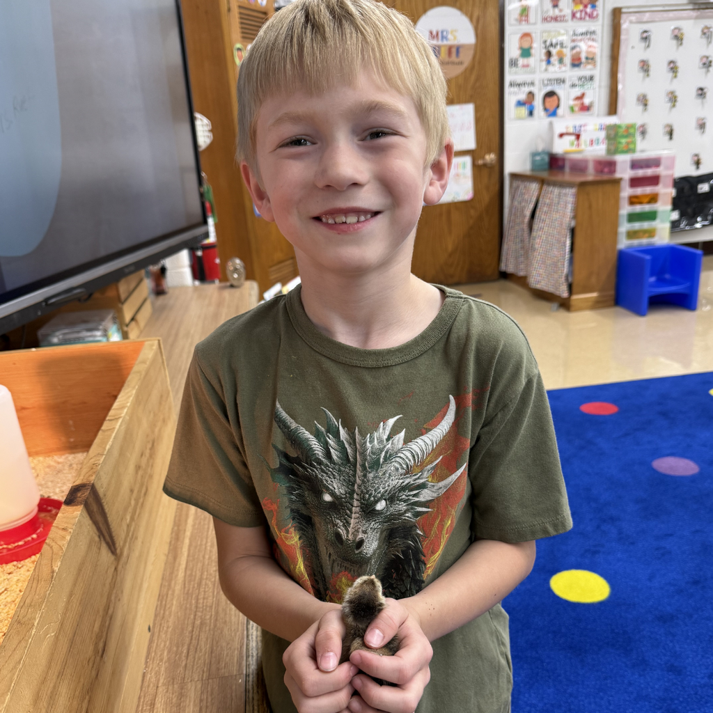 student holding chick smiling