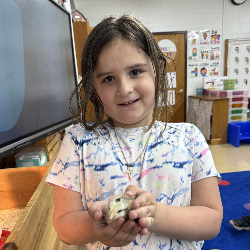 student holding chick smiling