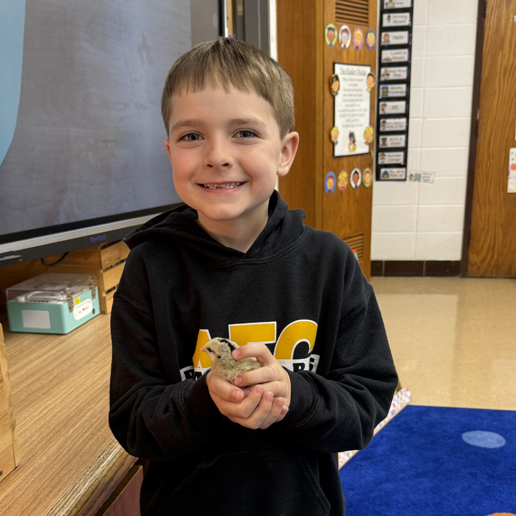 student holding chick smiling