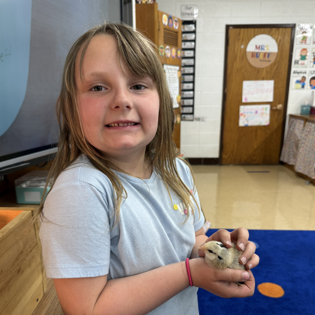 student holding chick smiling