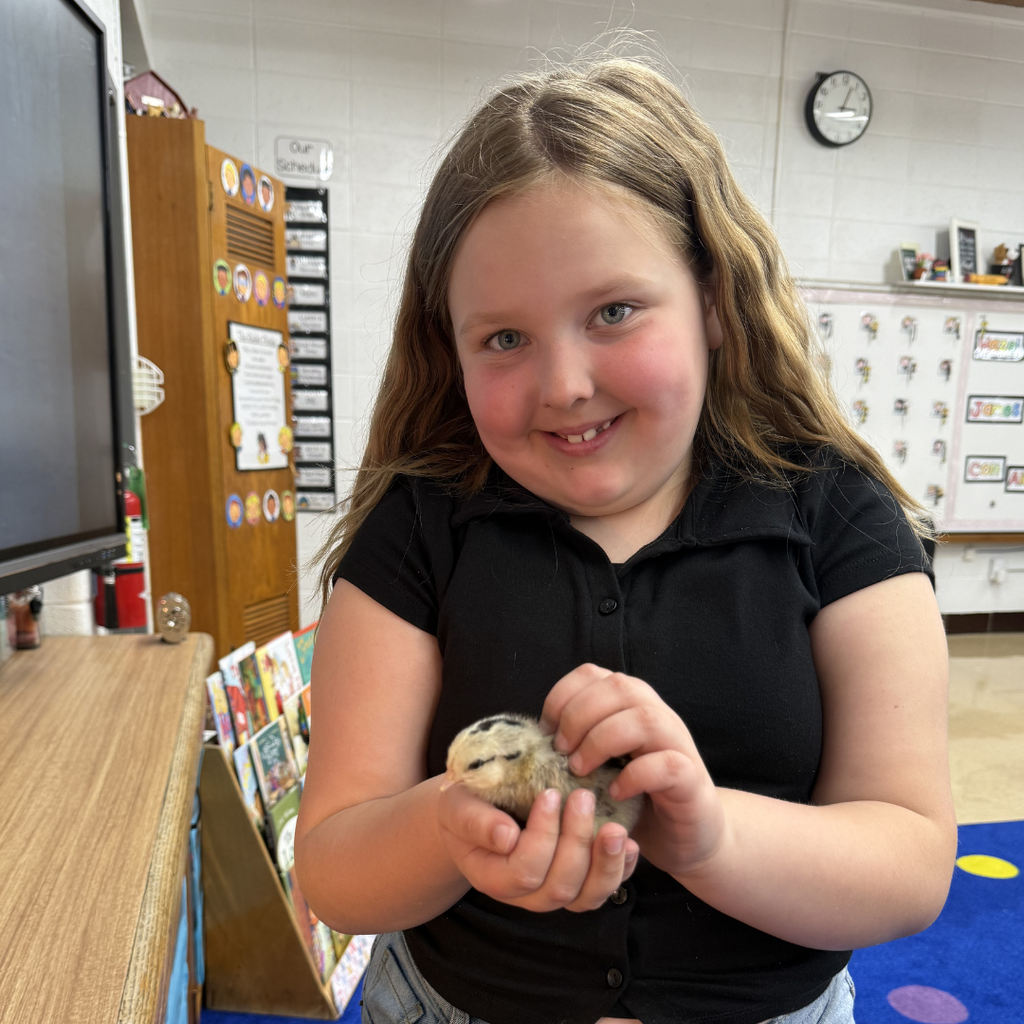 student holding chick smiling