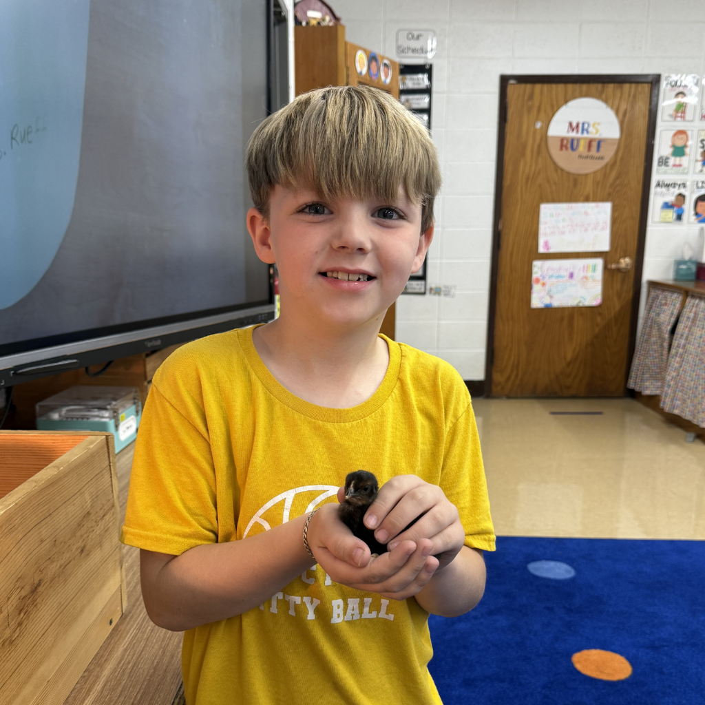 student holding chick smiling