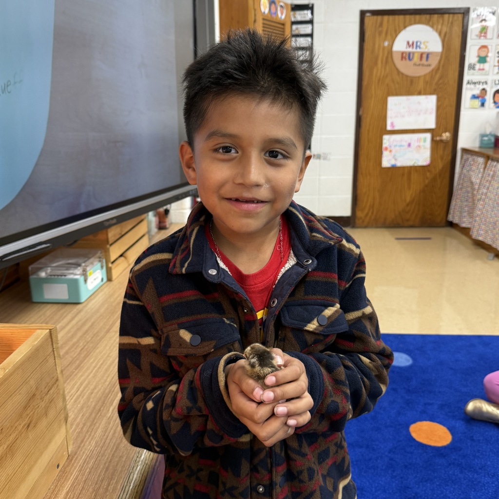 student holding chick smiling