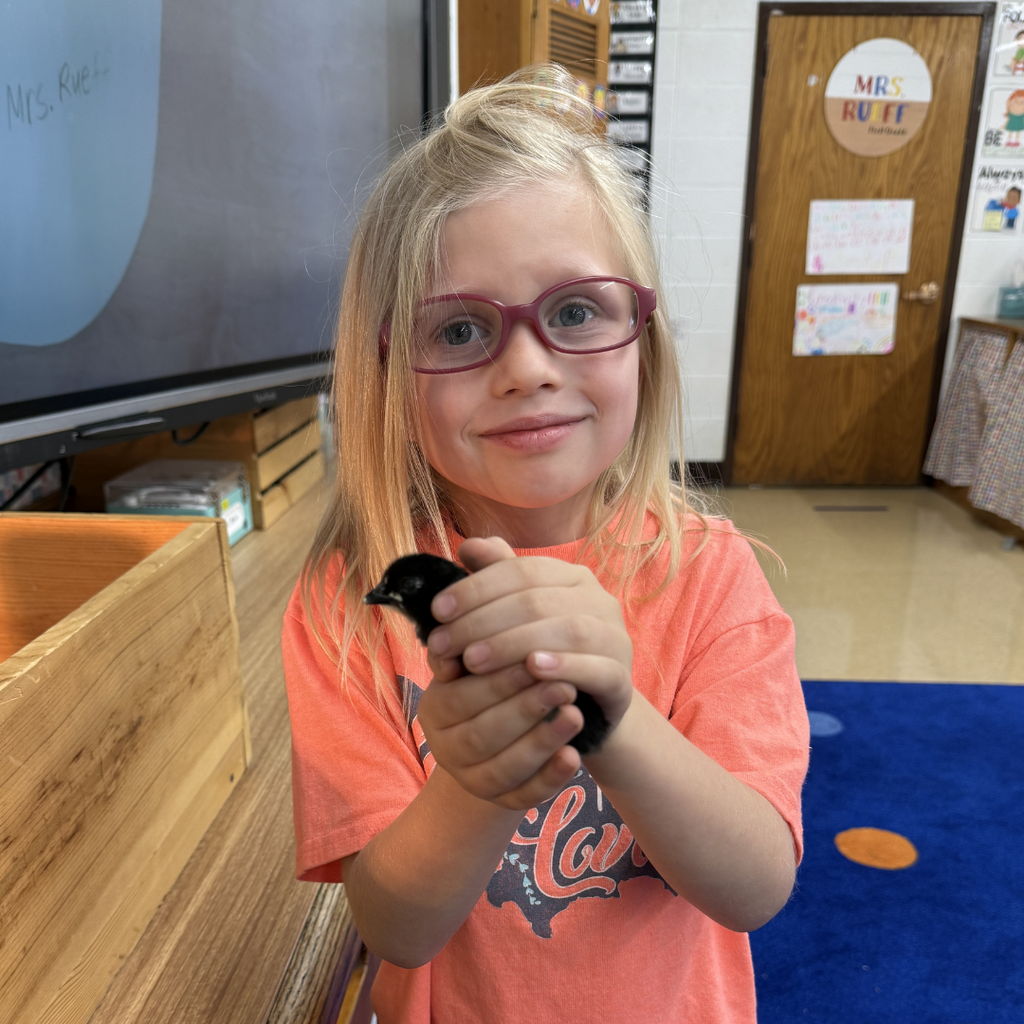 student holding chick smiling