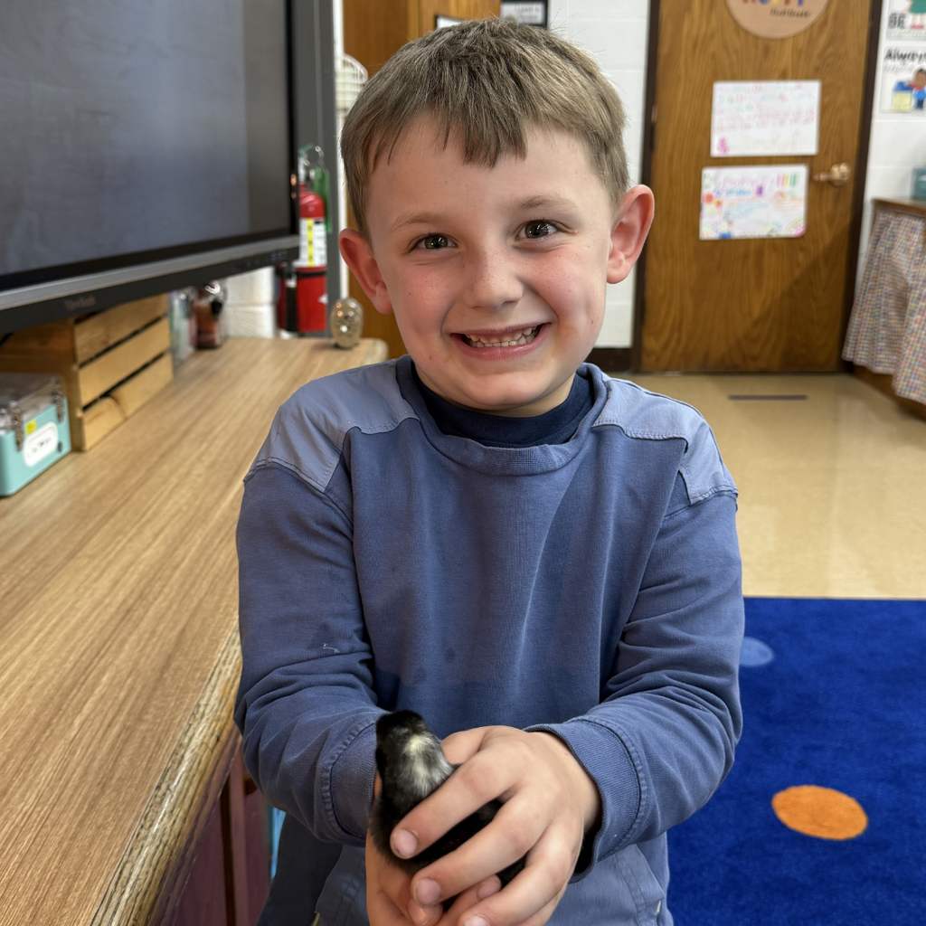 student holding chick smiling