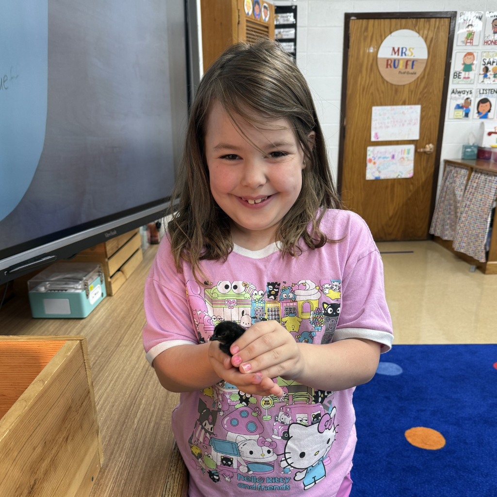 student holding chick smiling