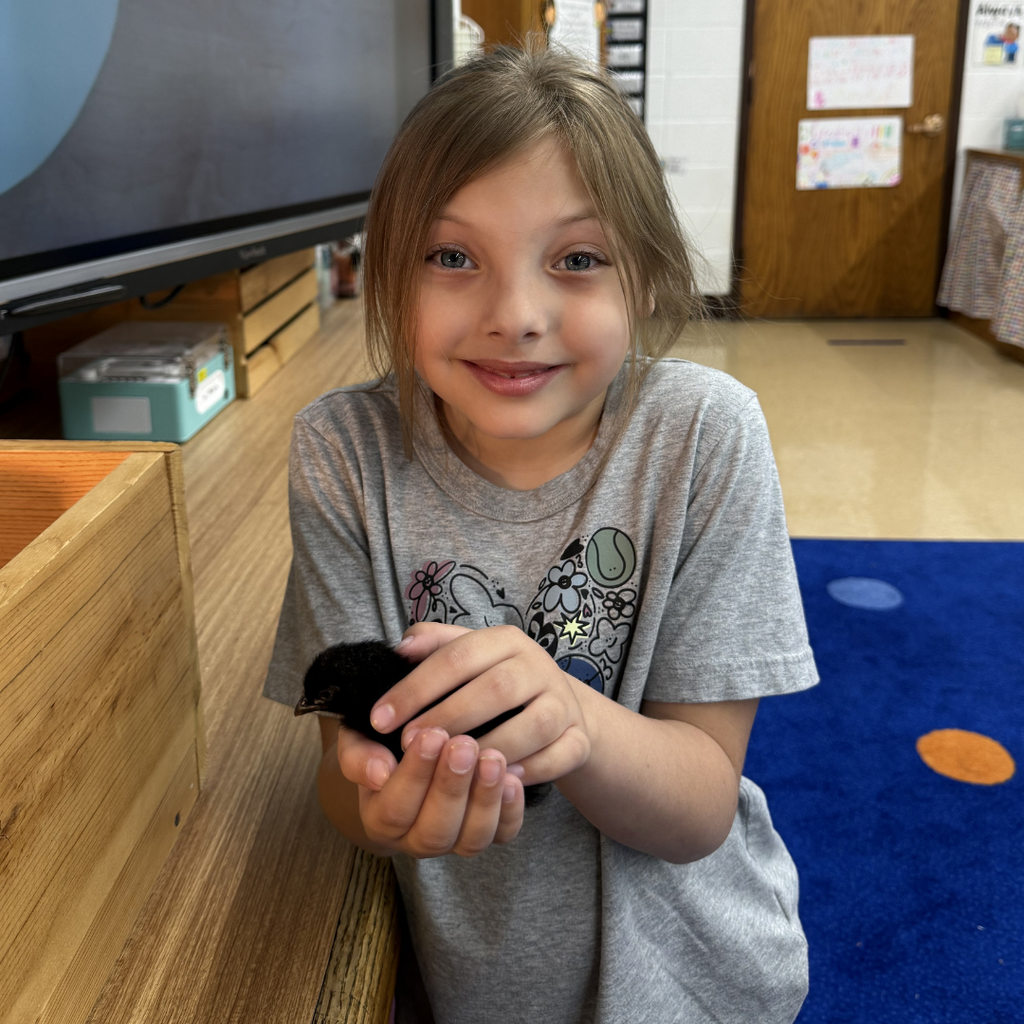 student holding chick smiling