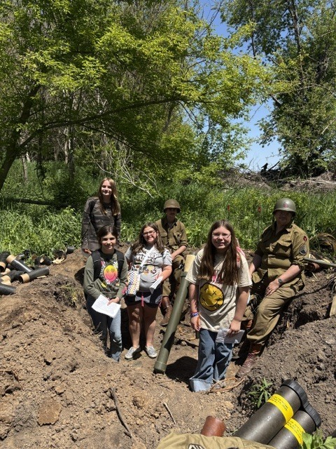 students posing with reenactment actors in ditch