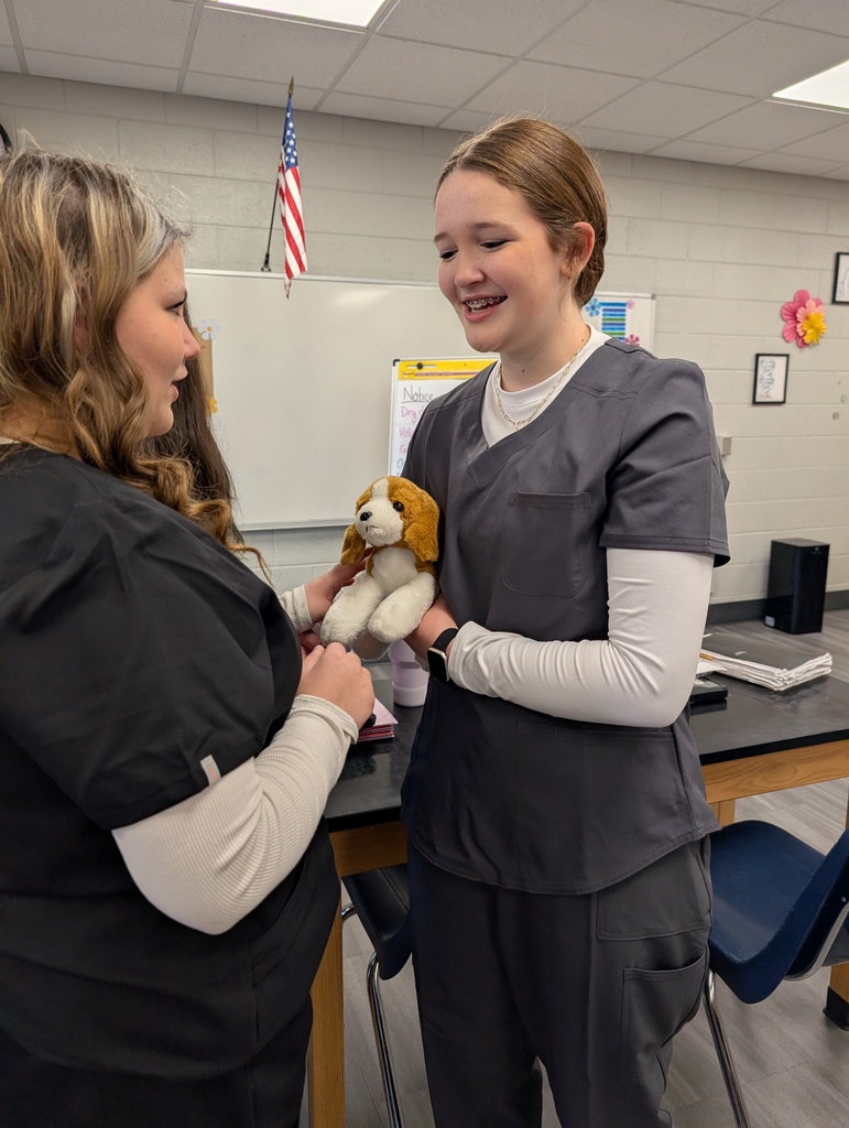 students smiling holding a stuffed dog
