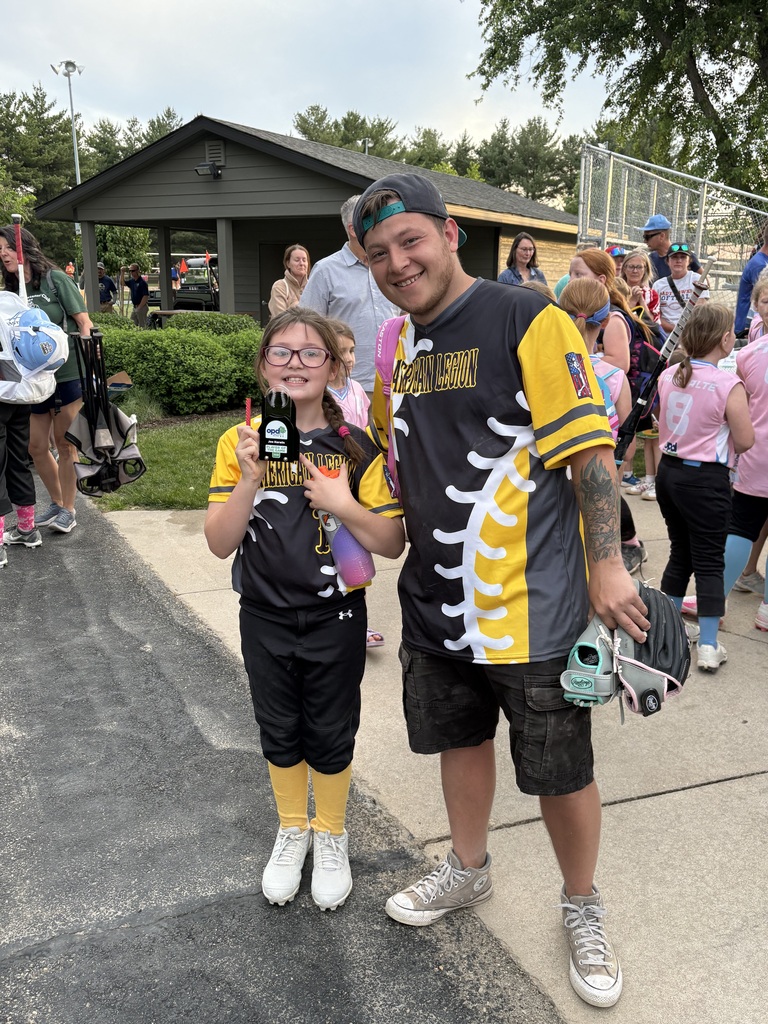 student posing with her coach, holding her trophy