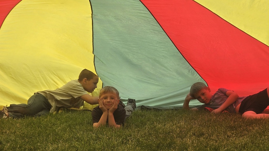 students playing parachute outside under the parachute