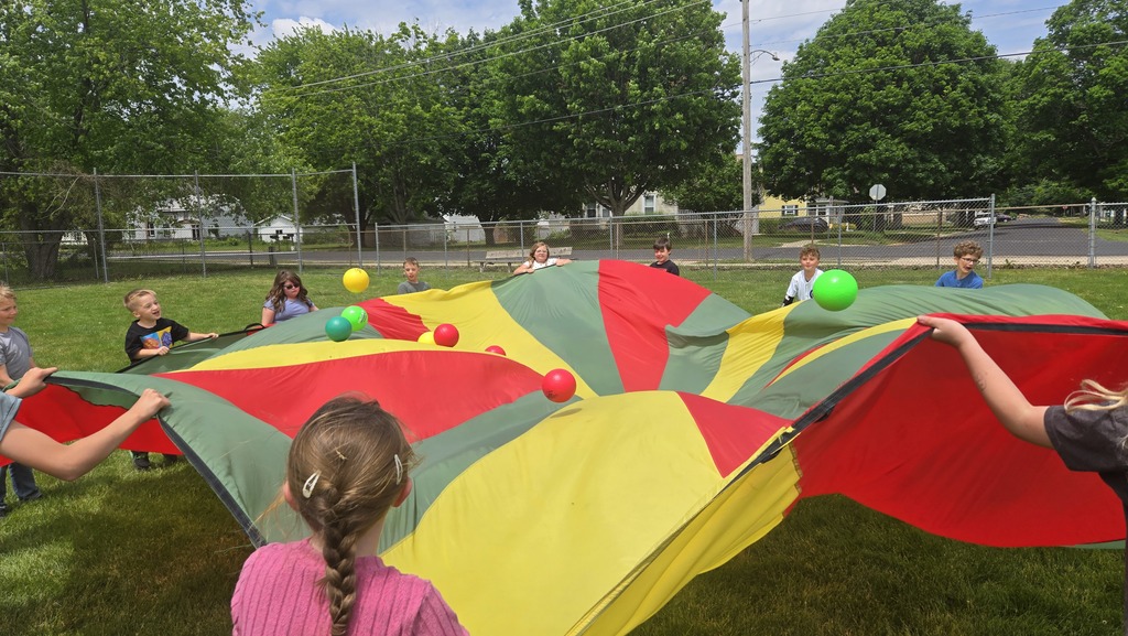 students playing parachute outside with balls on top