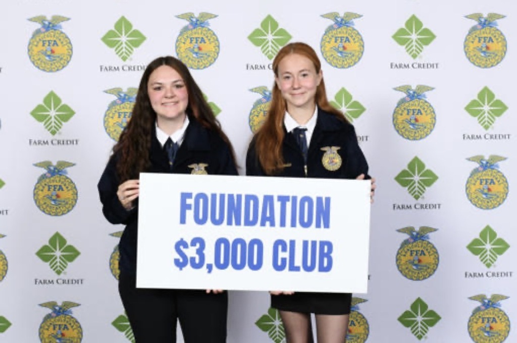 two girls holding large paper that says foundation $3,000 club