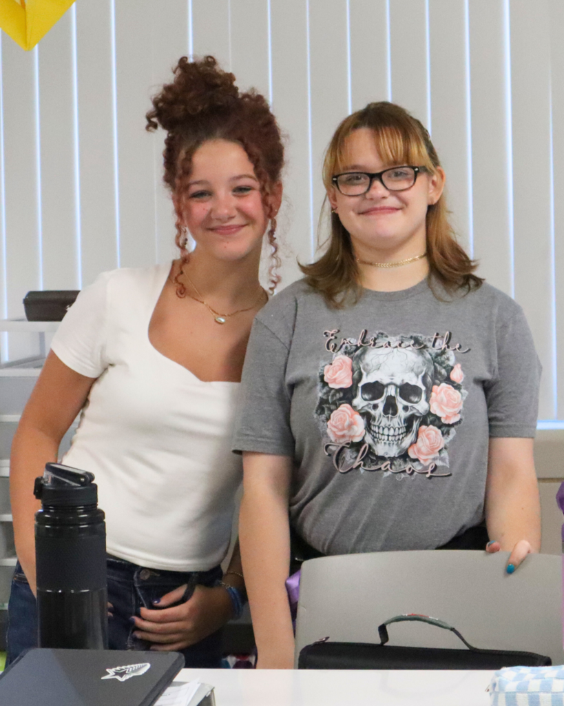 Two middle school girls look at the camera while smiling