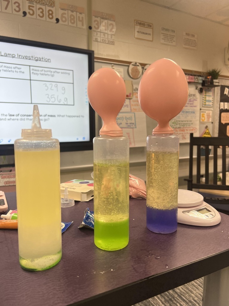 Three tall bottles with colorful liquid and fizzing tablets, two topped with inflated balloons showing gas release during the lava lamp experiment.
