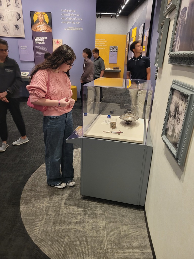 A student looks closely at artifacts inside a glass display case in a museum exhibit.