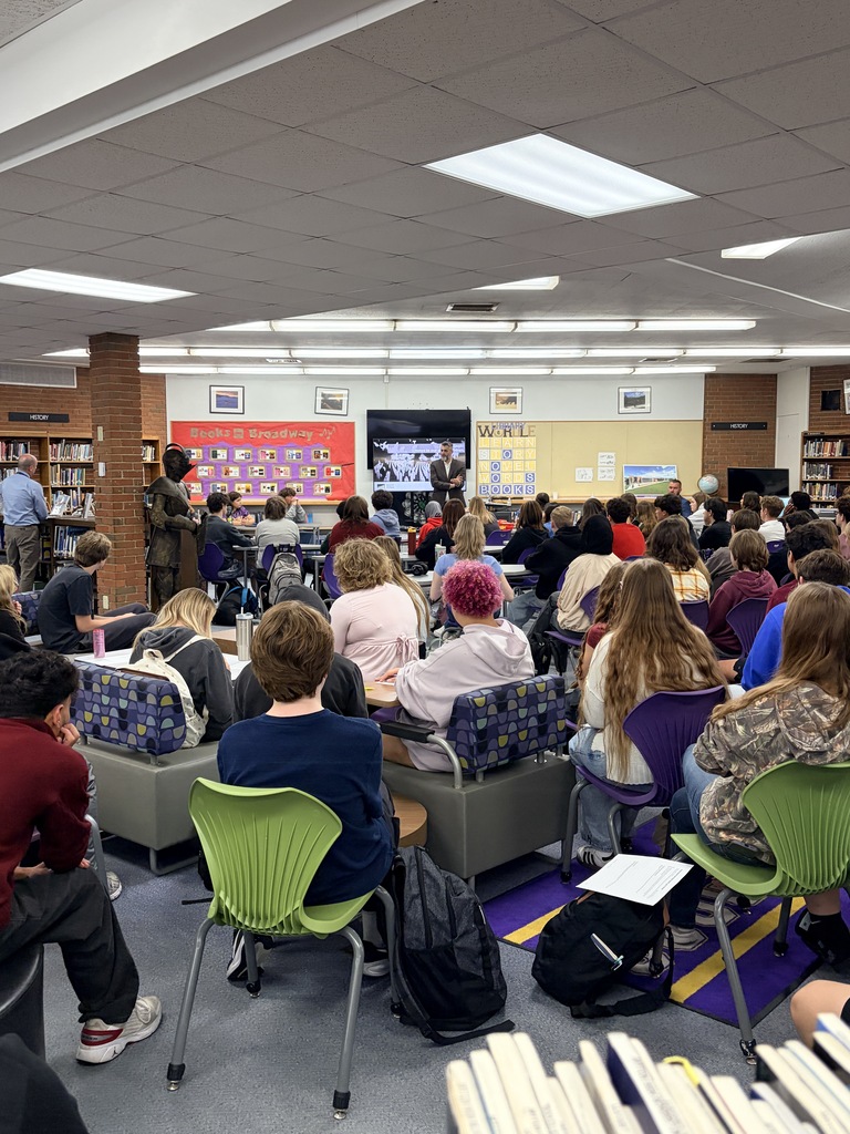 High school students sit in a library listening to a presentation by guest speaker Emir Suljagić.
