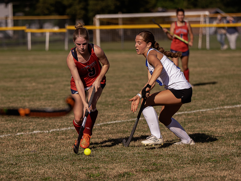 Afton player in action with field hockey stick. Opposing player trying to get the ball