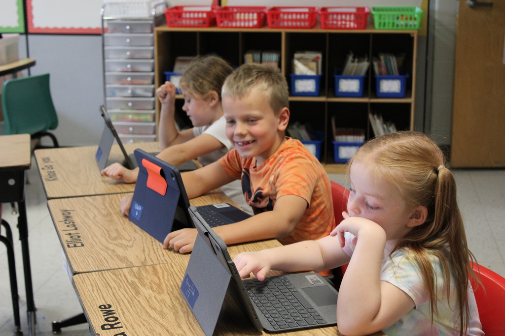 Afton student smiling while working on computer.