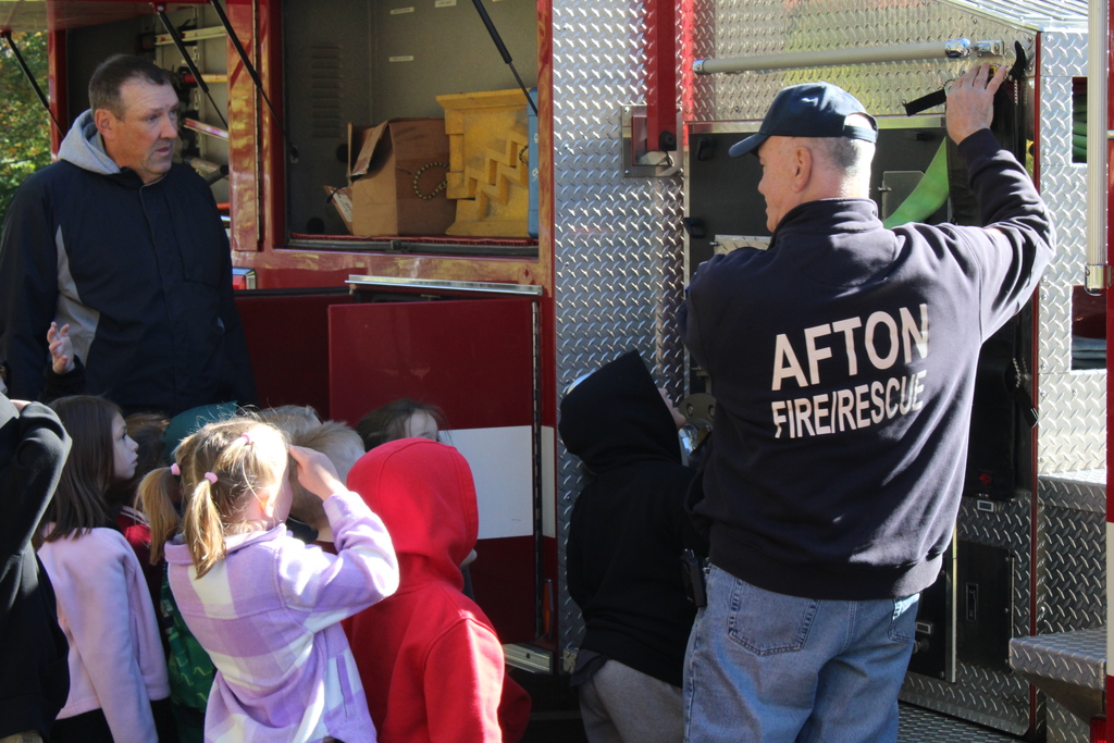 Afton Fire and Rescue worker showing kids and teacher the inner workings of a fire truck