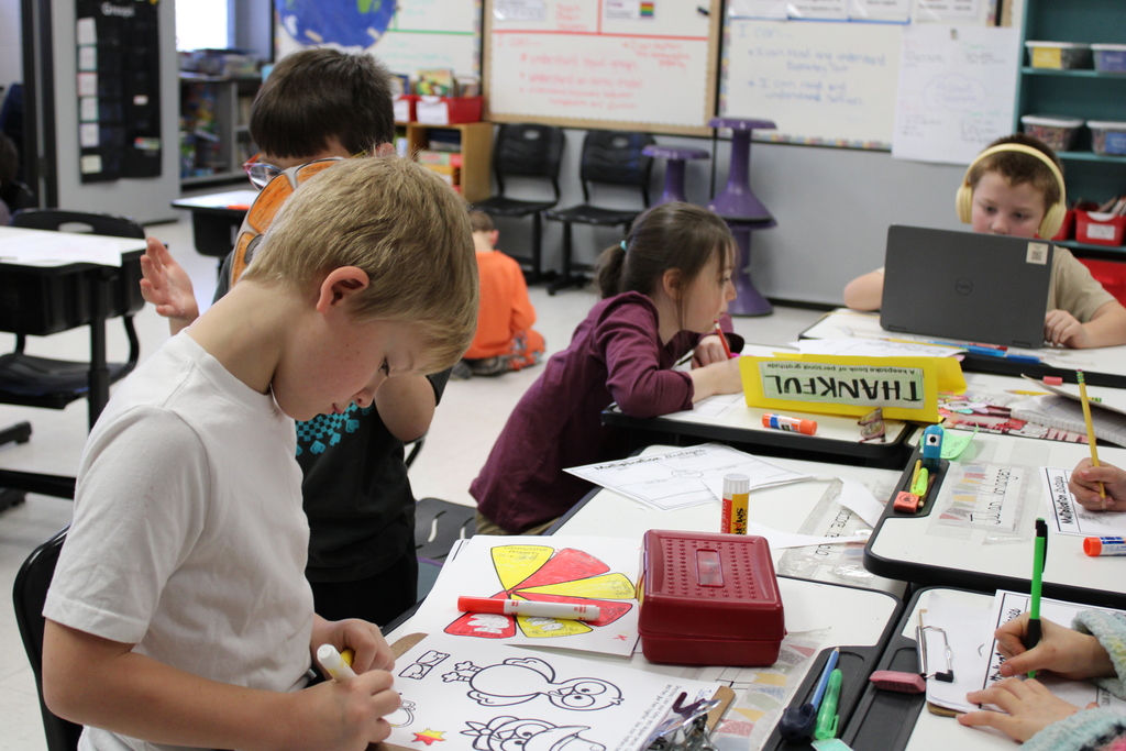 Students working in differentiated classroom. Two are coloring and one is on the computer