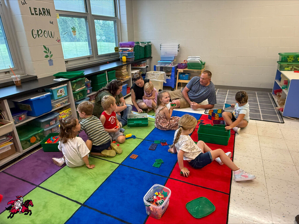 Pre-K and kindergarten students play with toys on the floor of their classroom