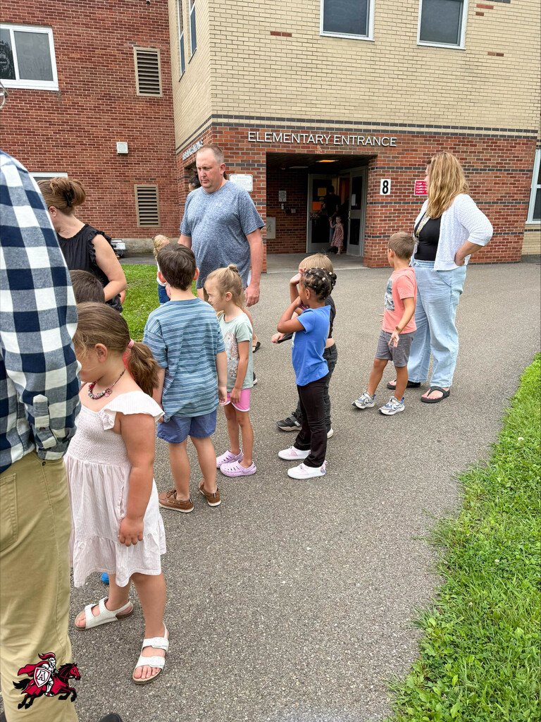 Pre-K and kindergarten students line up for the bus ride with their parents outside Afton Elementary School