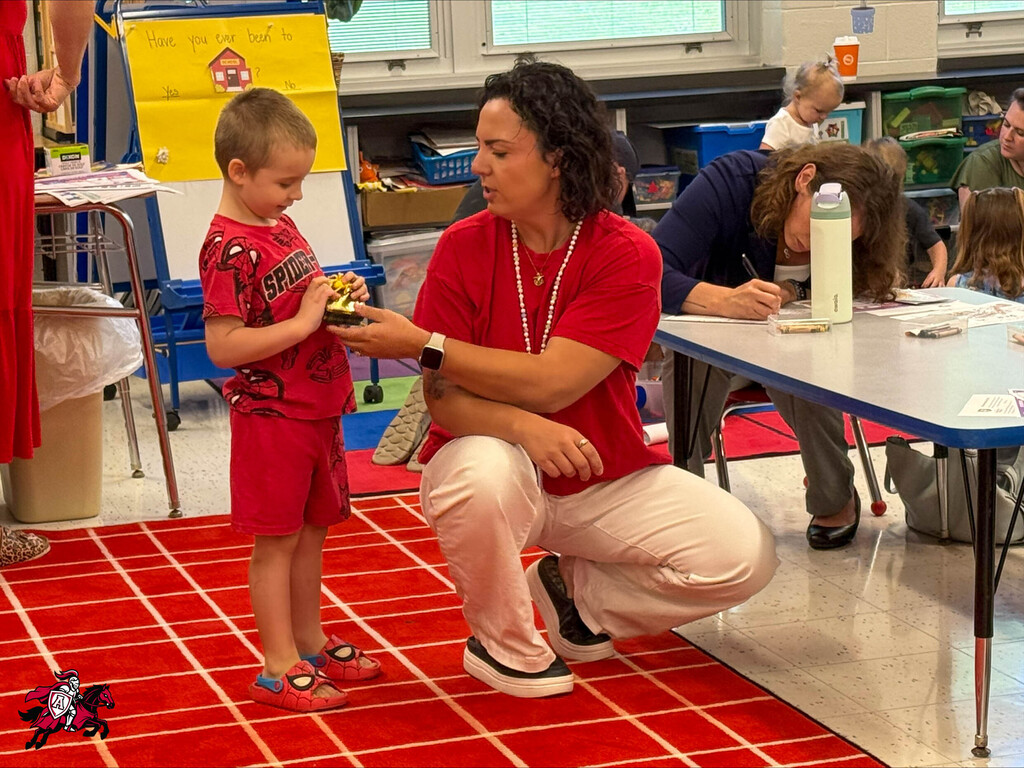 A teacher assists a student with a toy he is playing with