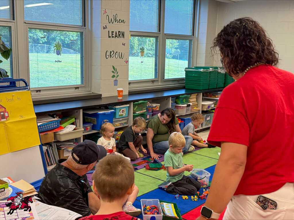 Pre-K and kindergarten students play with toys on the floor of their classroom