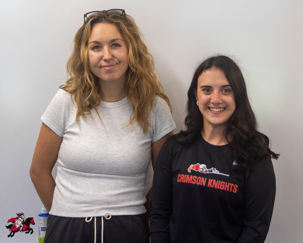 A photo of Morgan Mertz (left) standing next to Kaitlyn Hardler (right) in front of a white board