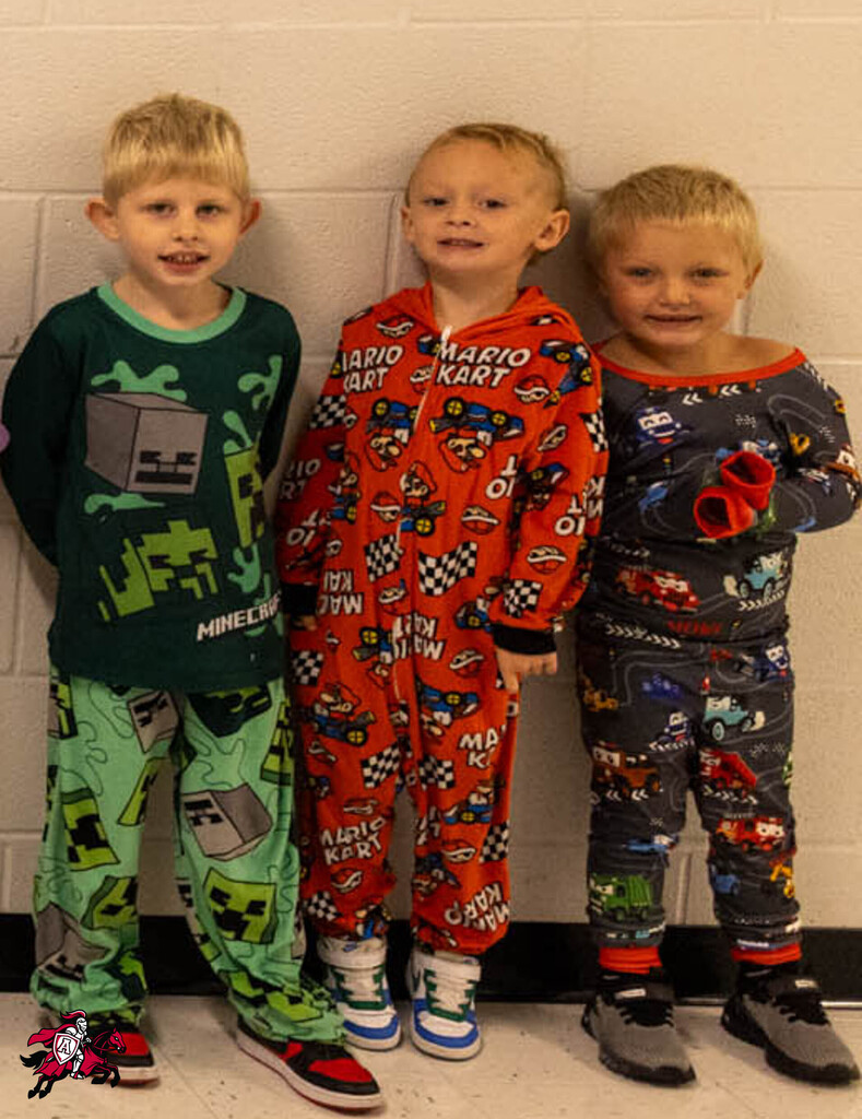 Three boys in pajamas, one in green, another in red, and the third in black, standing against a white wall.