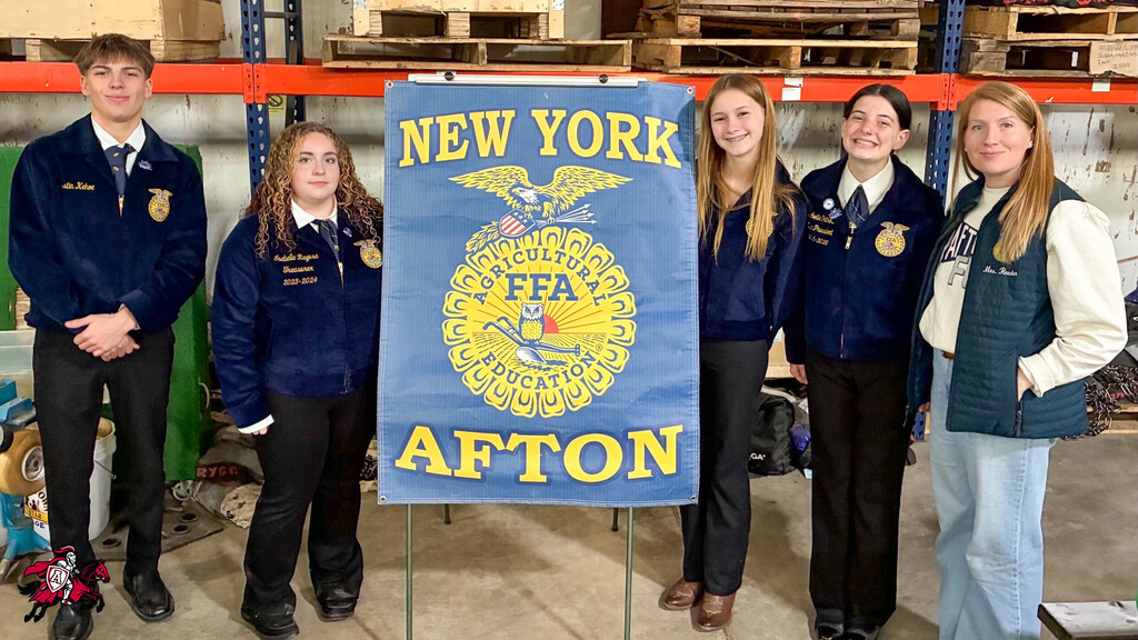 Five students stand behind a banner reading "New York FFA Afton". They are in blue jackets and black pants. A building with storage boxes in the background.