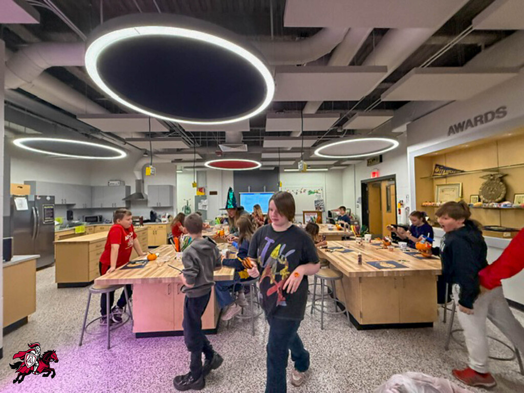 Kids in a kitchen area with a pink and white floor, working on tables and standing.