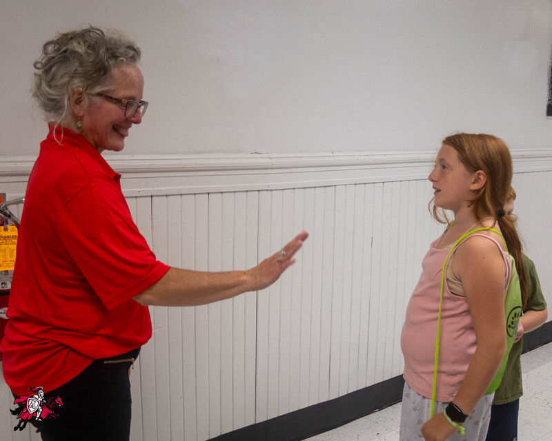 A teacher and a student have a conversation in the hallway of a school
