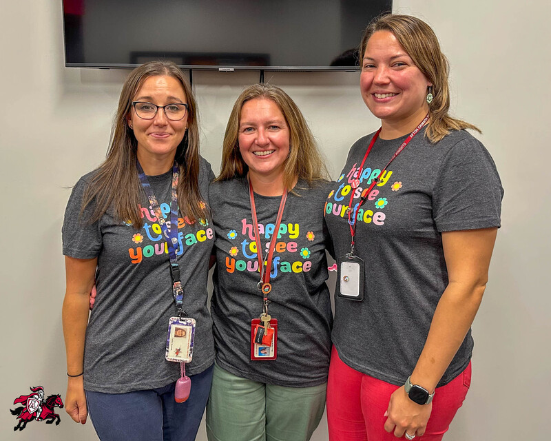 Three Afton Central School District counselors stand beside each other wearing the same shirt that reads, "Happy to see your face"
