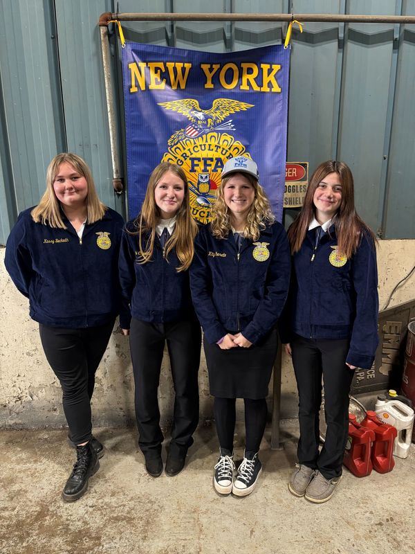 Smiling FFA students in uniform in front of the FFA banner