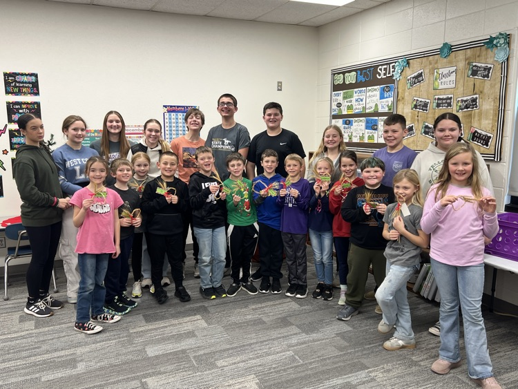 Second Graders wheat weaving with some great help from our friends, part of the Seventh Grade class.
