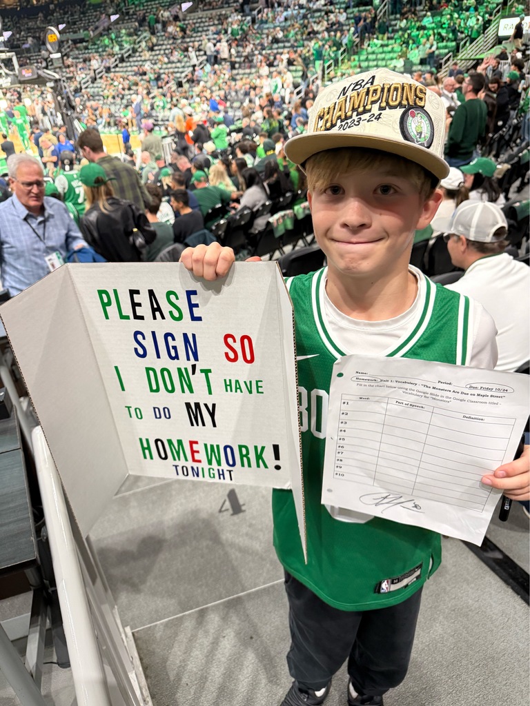 student holding signed homework and poster