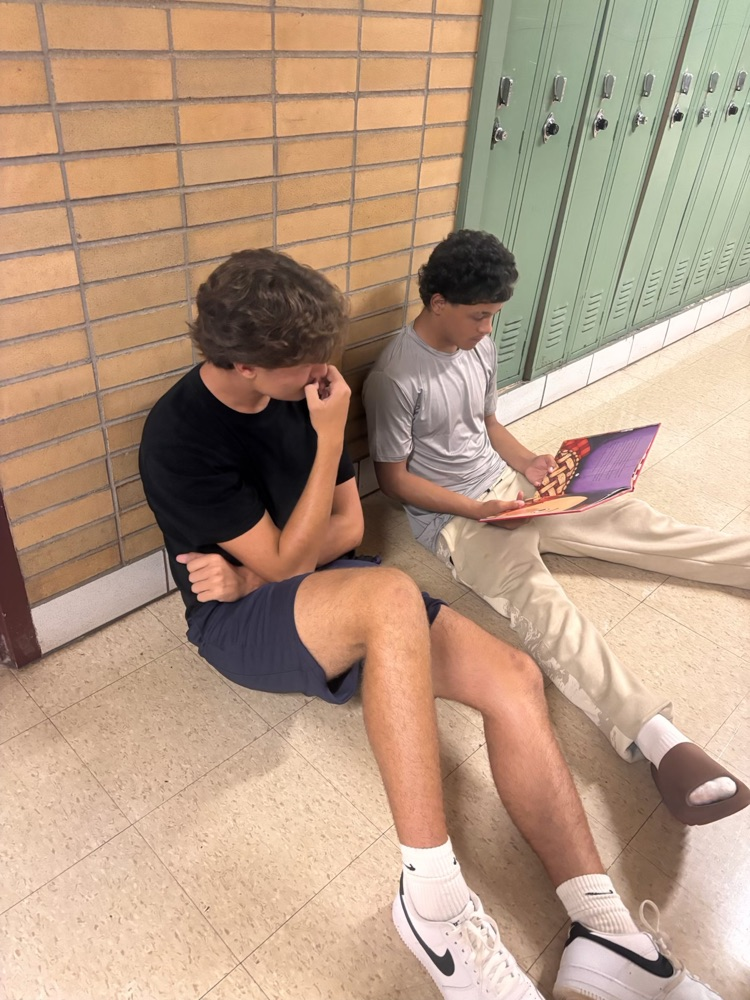 AHS students reading seated in the hallway