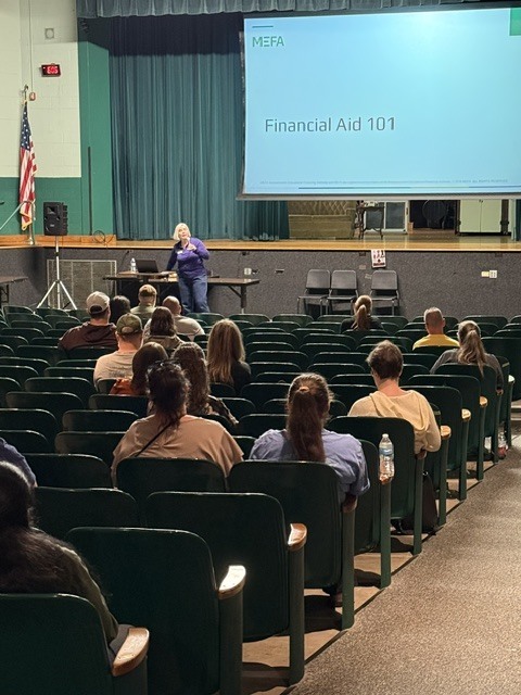 people sitting in AHS auditorium viewing financial aide presentation