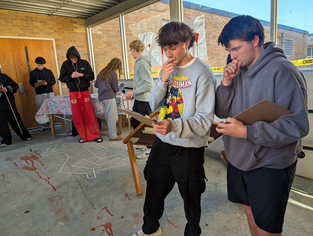 students in forensics science class examining a fake crime scene in the hallway