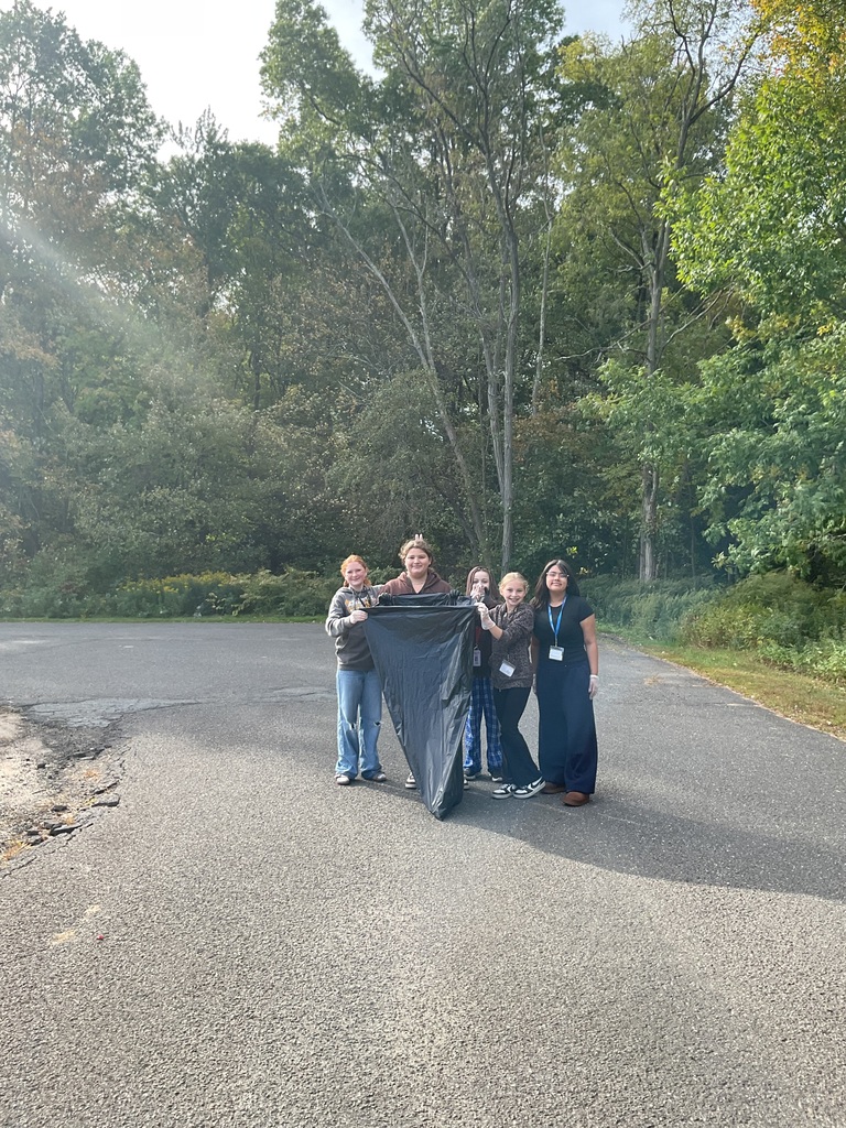 students posing with trash bag outside ready to cleanup the trash